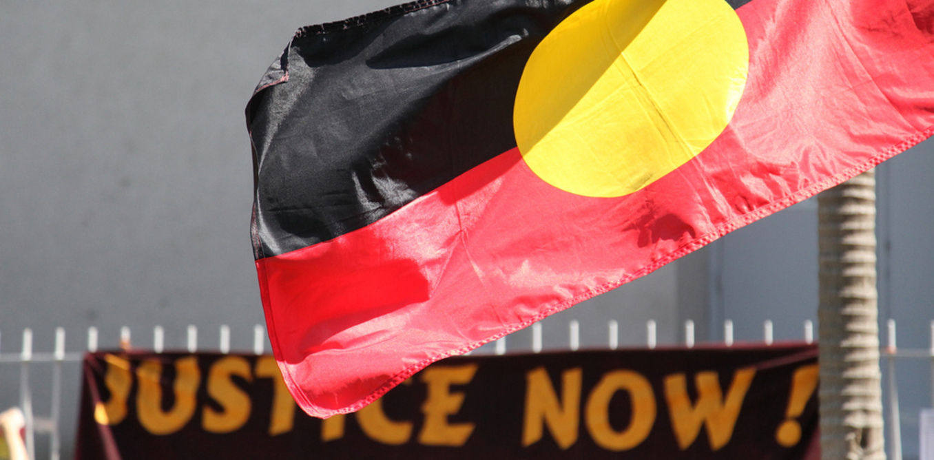 Aboriginal flag with justice now sign