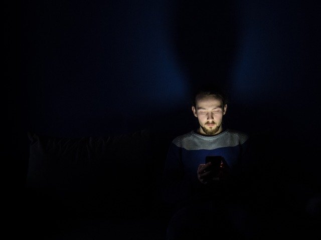male looking at a screen in the dark