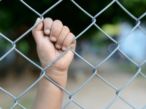 Child's hand holding wire in detention