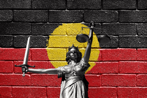 Lady Justice in front of Aboriginal flag