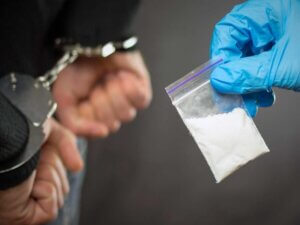 White powder drug such as cocaine or heroin seized from arrested man in handcuffs