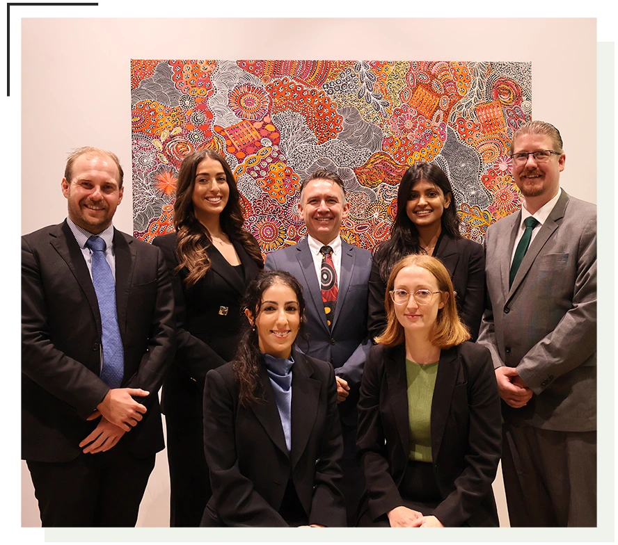 Seven professionals posing in front of a vibrant, intricate artwork, dressed in formal business attire.