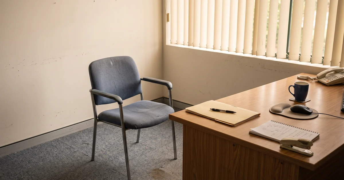 Empty chair facing a desk in a small plain office