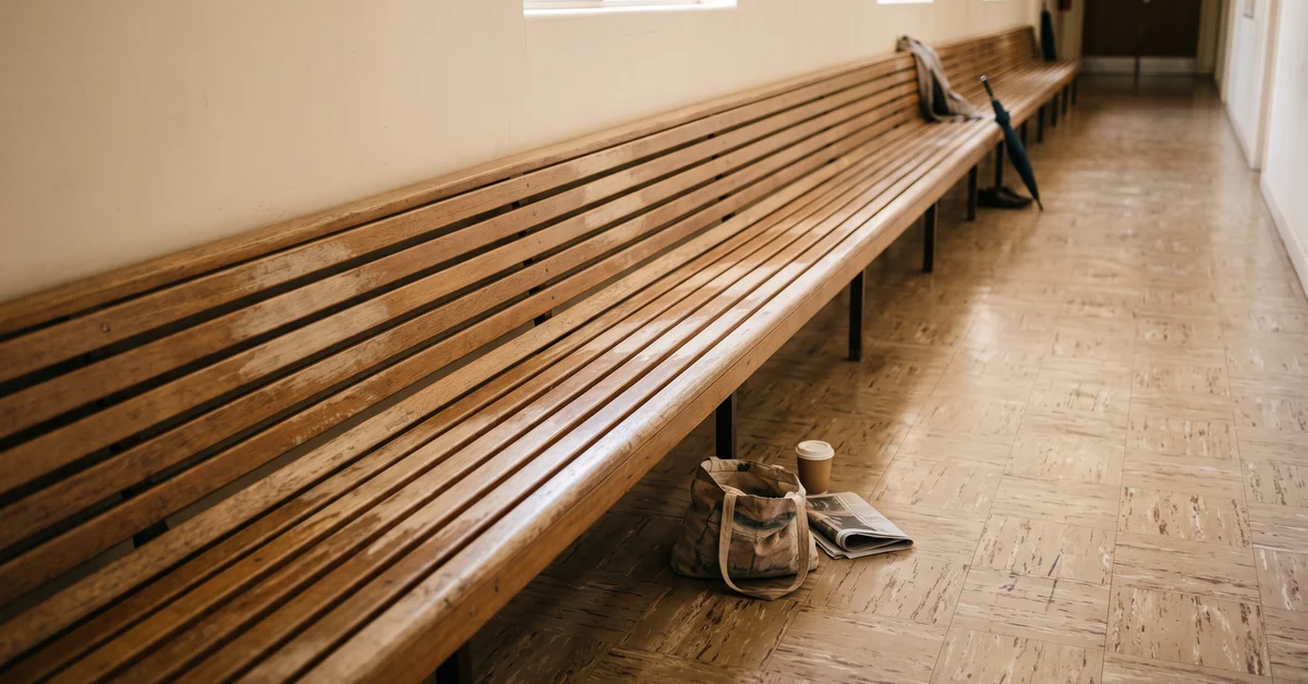 Long worn bench seat in a bare institutional corridor