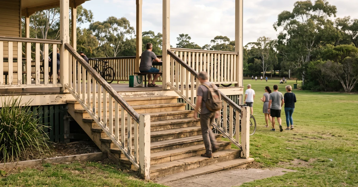 People on a beige wooden pavilion with stairs; a man with a backpack climbs the steps while others stand or walk nearby in a park setting.