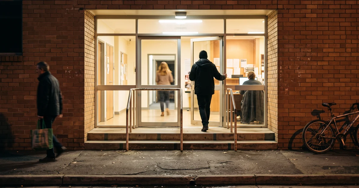Lit doorway of a police station at night seen from the footpath