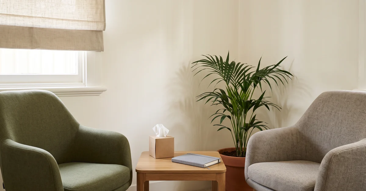 Two chairs and a side table in an empty clinician's consulting room