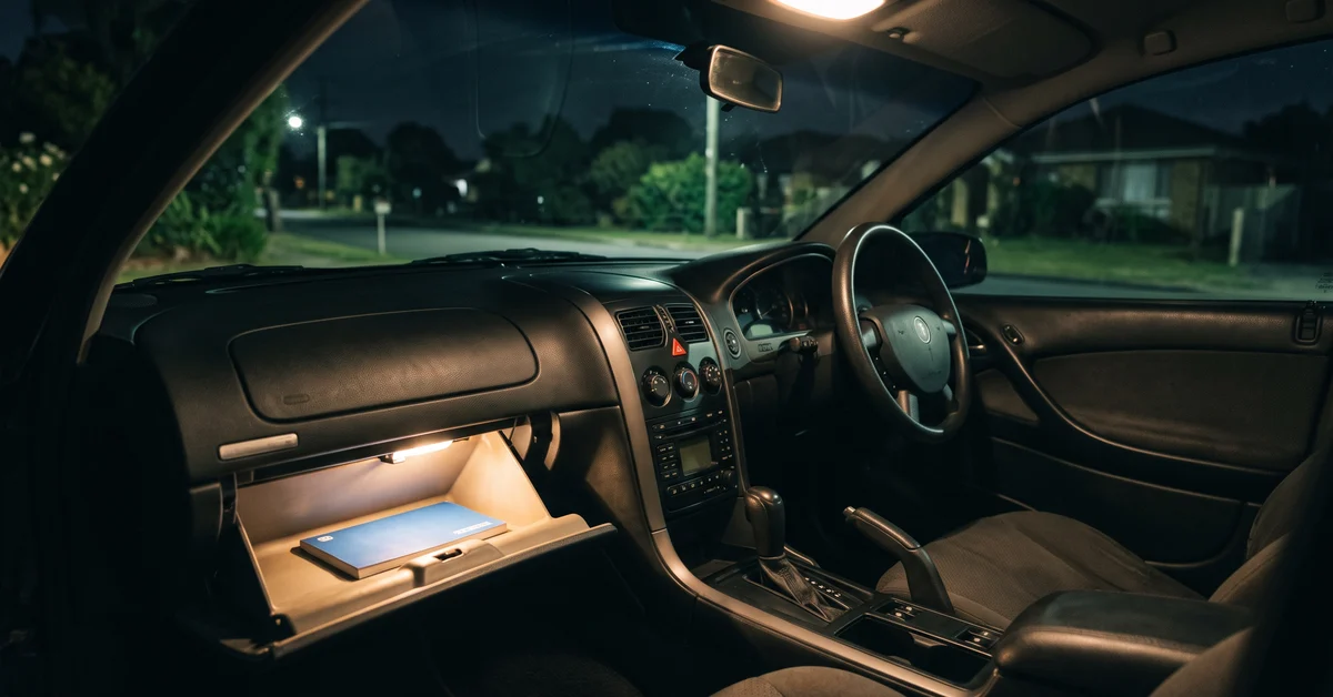 Open glovebox of a car at night with the interior light on