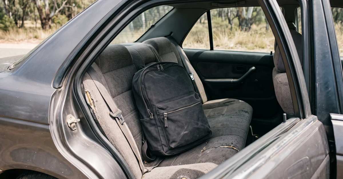 Plain backpack on the rear seat of a car with the door open