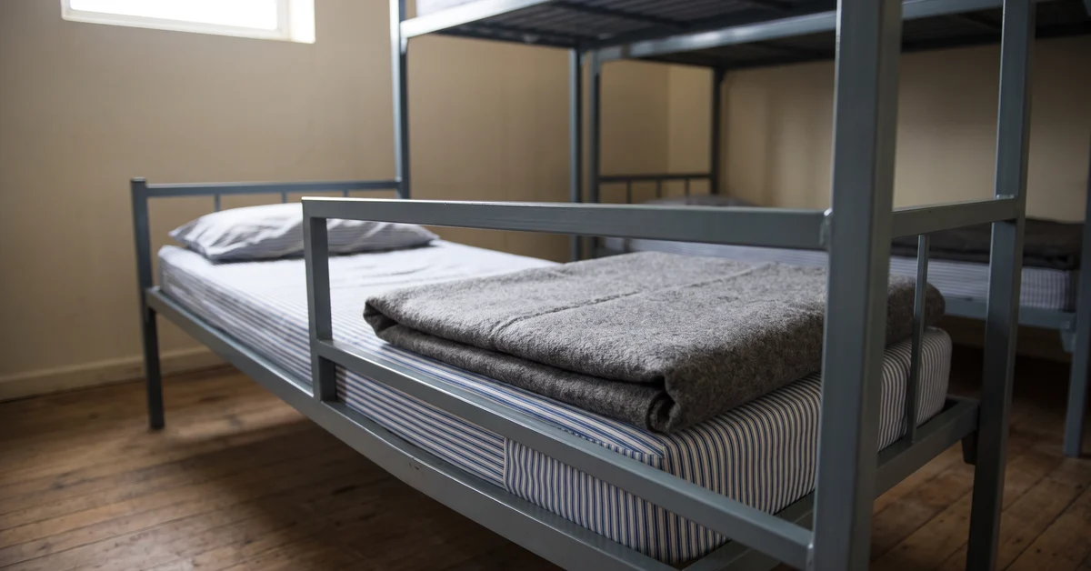 Folded grey wool blanket on the end of a steel bunk
