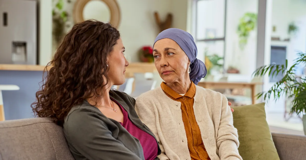a mother and adult daughter sit on sofa facing each other