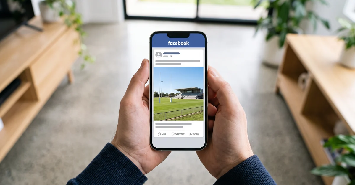 Hands holding a phone showing a sports meme page post with an empty rugby league ground