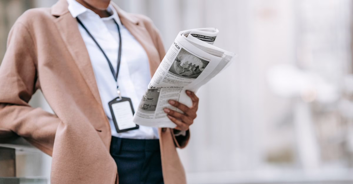 A woman in office clothes reading a newspaper