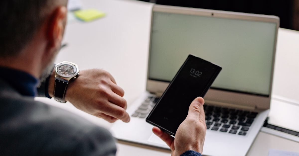 Convert stalking | O'BRIEN CRIMINAL & CIVIL SOLICITORS a man's hand holding a mobile phone in his hand with a opened laptop in the background, both screens both blank
