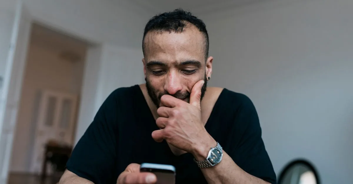 a man looking at his mobile phone whilst sitting down