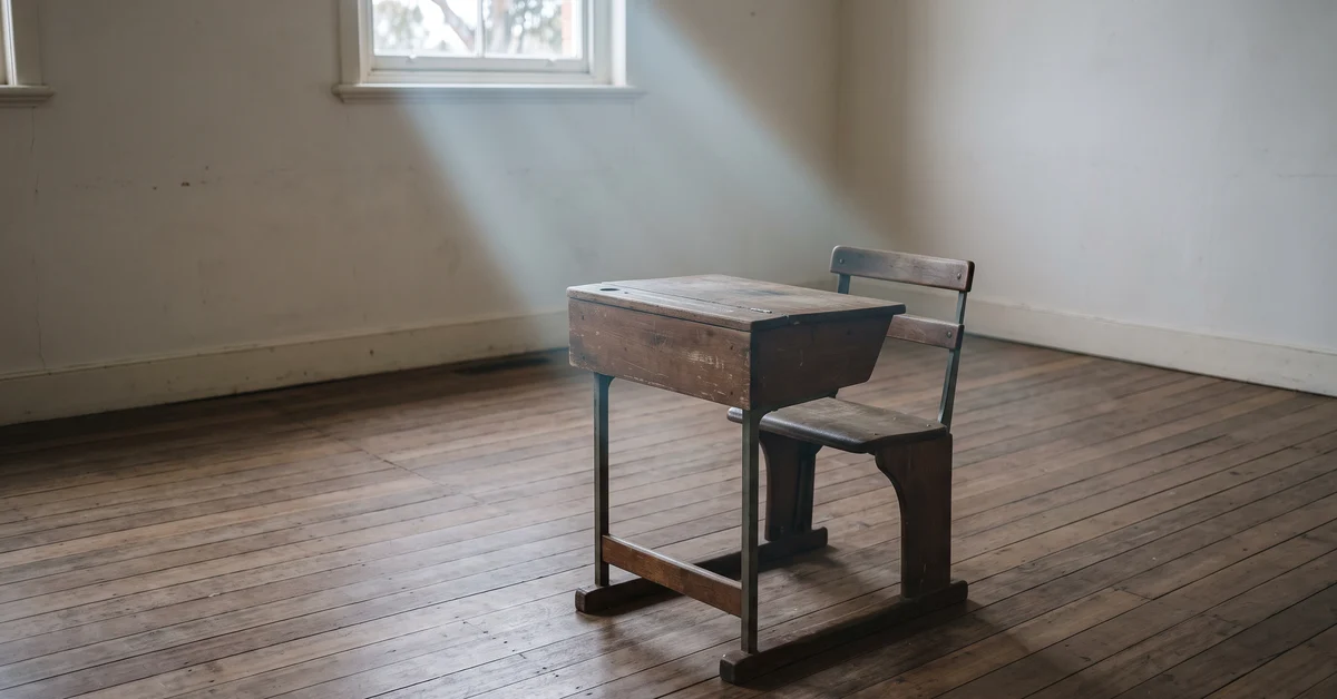 Single empty school desk in a shaft of light