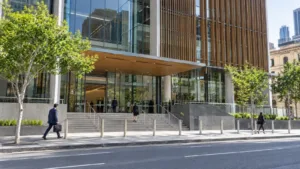 Lawyers in business attire walking toward the entrance of a modern glass and timber courthouse building in Brisbane